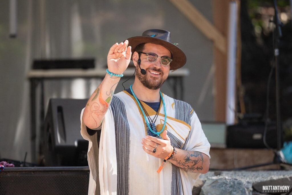 Kamel, founder of NotYourTypicalShaman, waving during a shamanic breathwork session